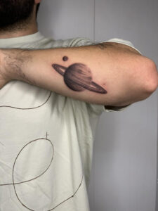 קעקוע של כוכב שבתאי בסגנון הצללות על האמה